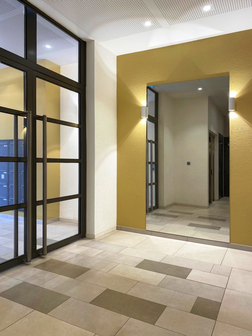 Hall d'entrée jaune et anthracite, avec un grand miroir, designé par Interface design pour un promoteur