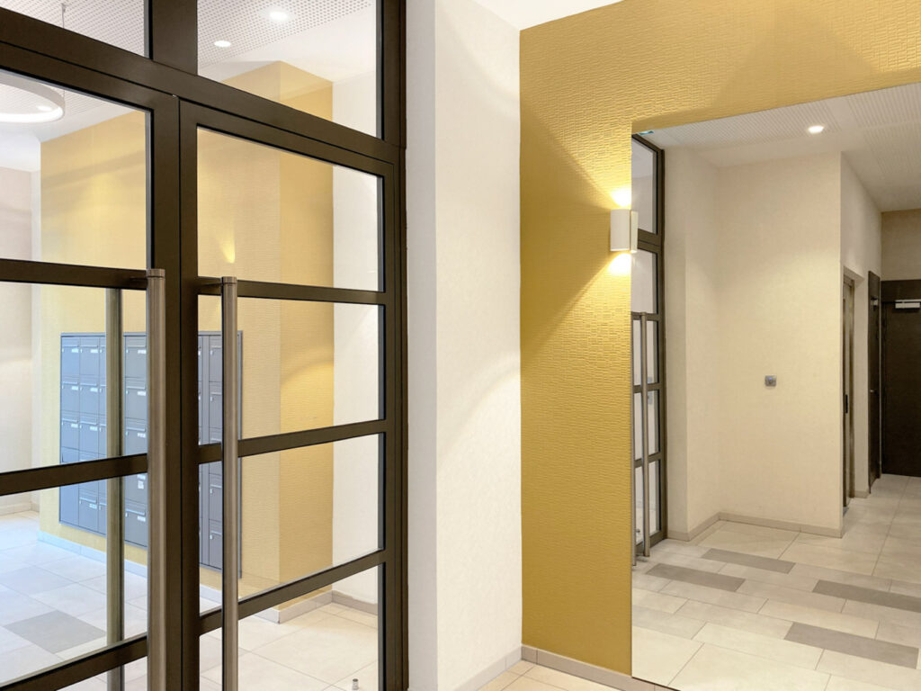 Yellow and anthracite entrance hall, with a large mirror, designed by Interface design for a promoter