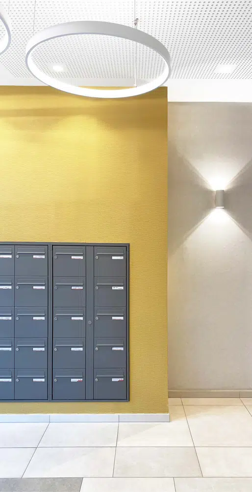 Hall d'entrée jaune et anthracite, avec un grand miroir, designé par Interface design pour un promoteur