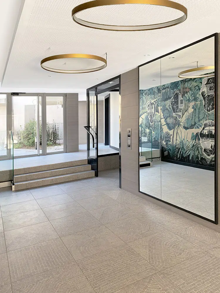Hall d'entrée blanc et or, avec un grand miroir, designé par Interface design pour un promoteur